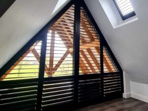 Zwarte Special Line houten shutters in de vorm van een driehoek, achter schuine ramen